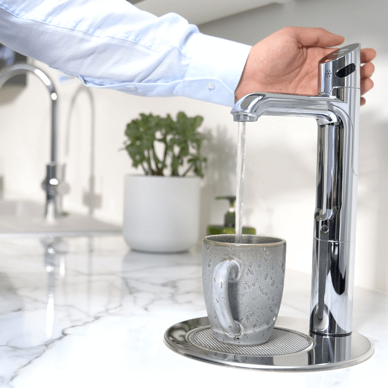 Filtered water tap dispensing hot water into a mug in a business kitchen