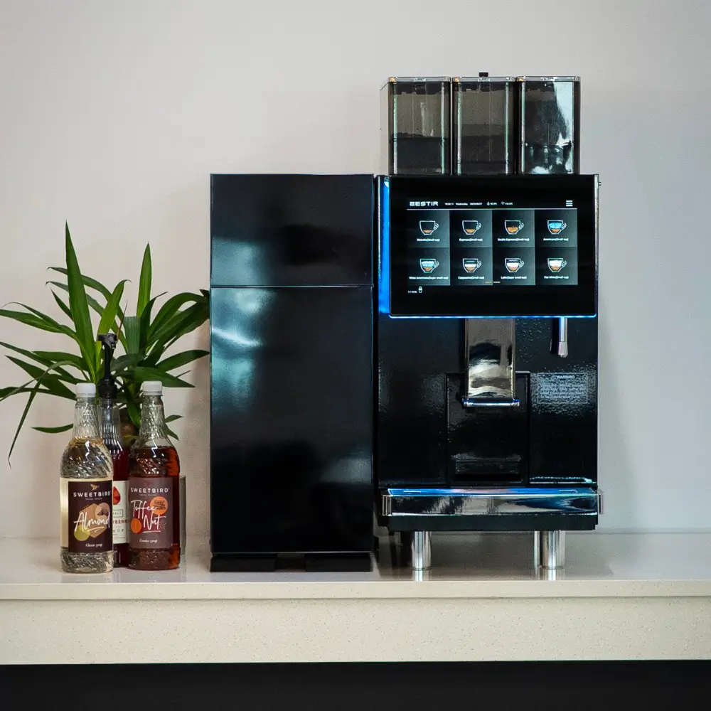 Commercial bean-to-cup coffee machine dispensing fresh coffee in an office setting.